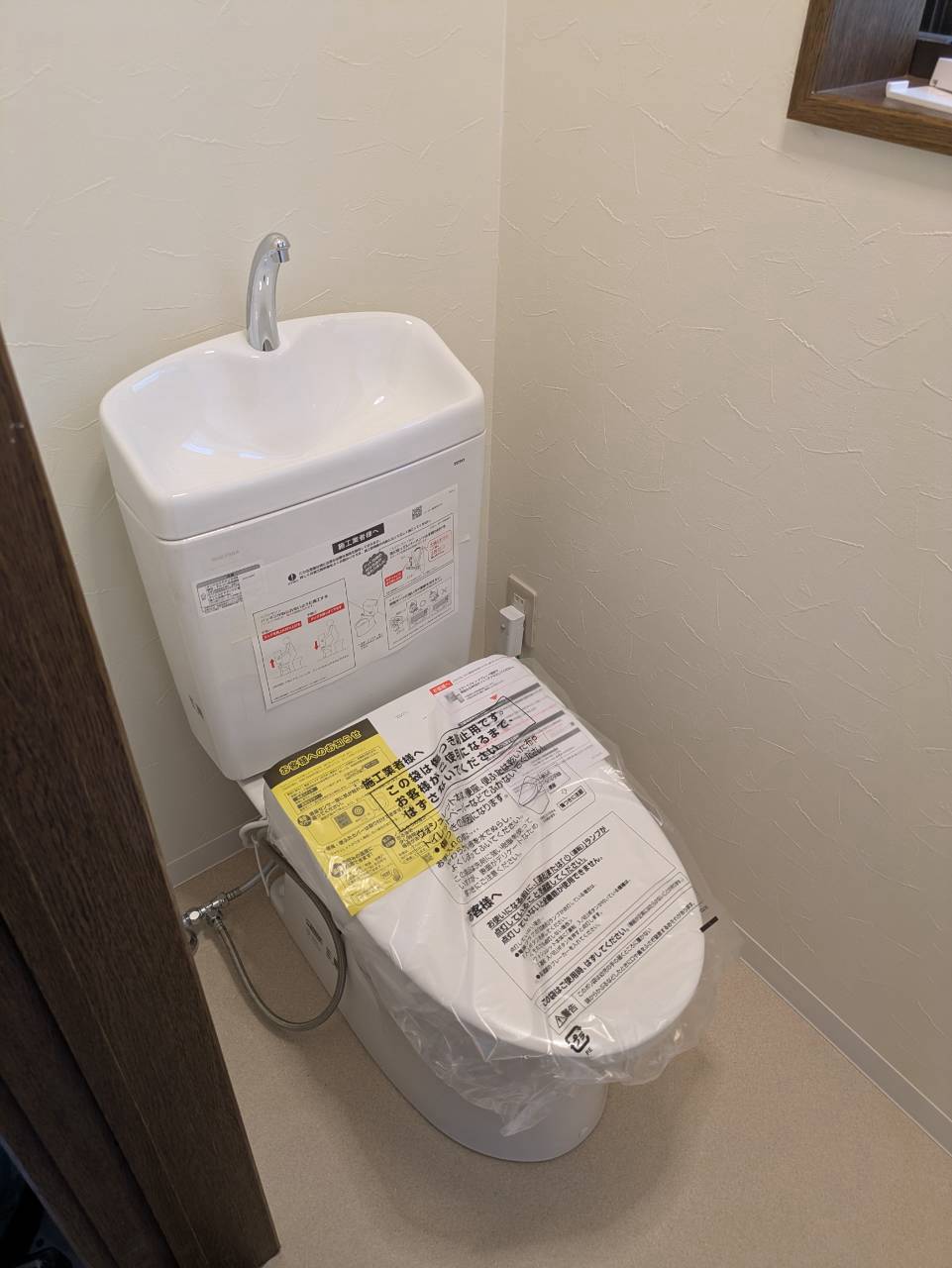 施工後：新しく設置された洋式便器と、張り替えた壁紙